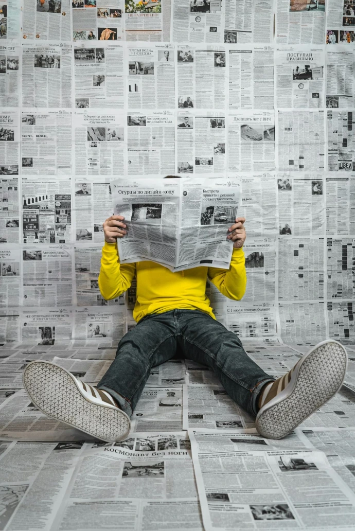a person sitting on the floor reading a newspaper